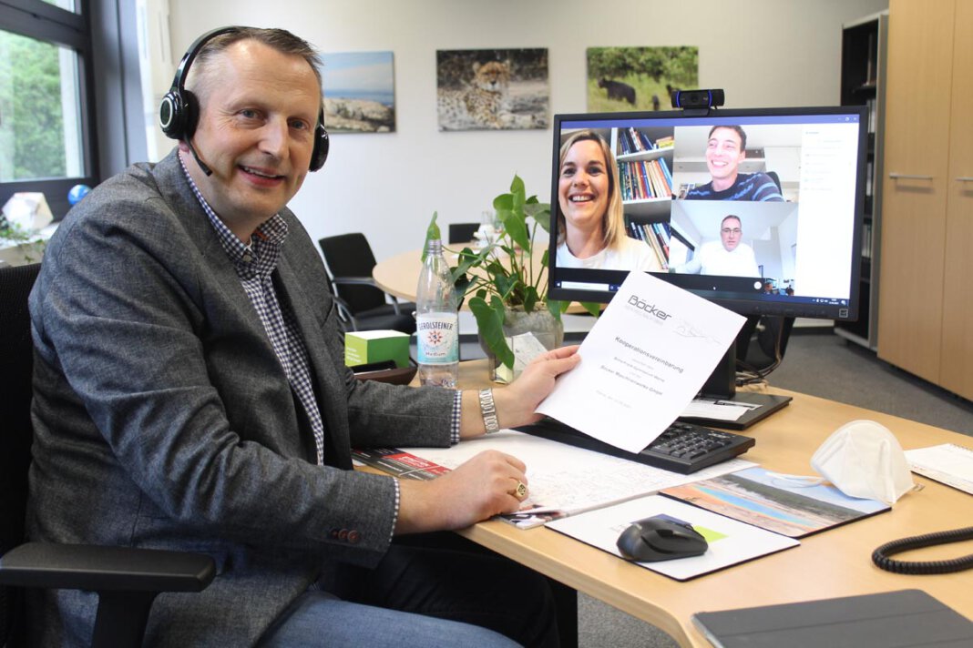 AFG Böcker Das Foto zeigt Schulleiter Marcel Damberg am Schreibtisch mit dem Vertrag in der Hand in digitaler Runde mit MINT-Koordinatorin Julia Krickau, Koordinator Berufliche Orientierung Marius Gregg, Personalchef Martin Lauer (auf dem Bildschirm). Foto: AFG