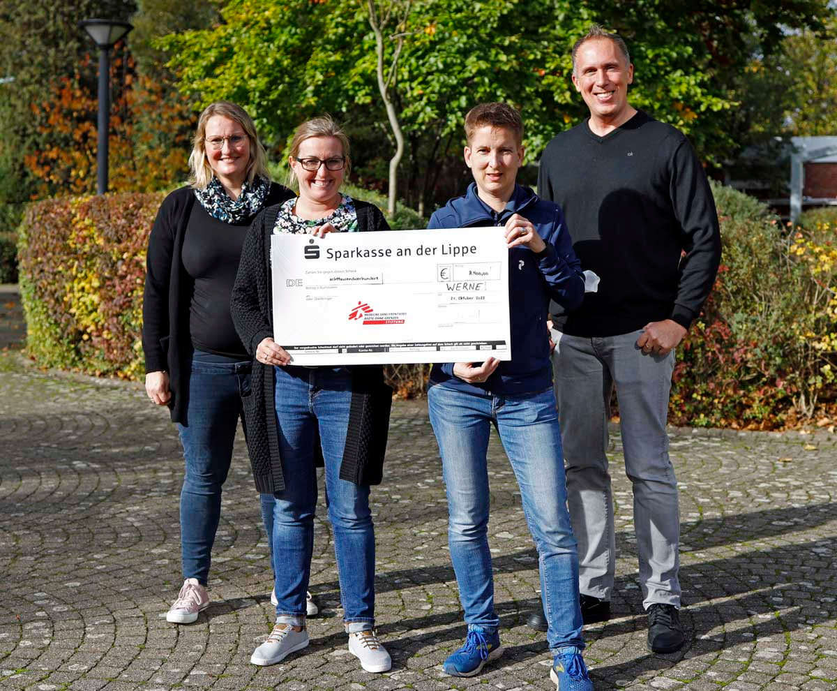 Die Organisatorinnen des Spendenlaufs am Gymnasium St. Christophorus präsentieren mit Schulleiter Thorsten Schröer den Spendenscheck für 