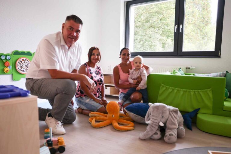 Landrat Mario Löhr mit den selbständigen Kindertagespflegepersonen Dilek Yesil und Sevgi Kancner, die die kleine Louisa auf dem Schoß hat. Sie besucht die Großtagespflege zur Eingewöhnung. Foto: Max Rolke – Kreis Unna