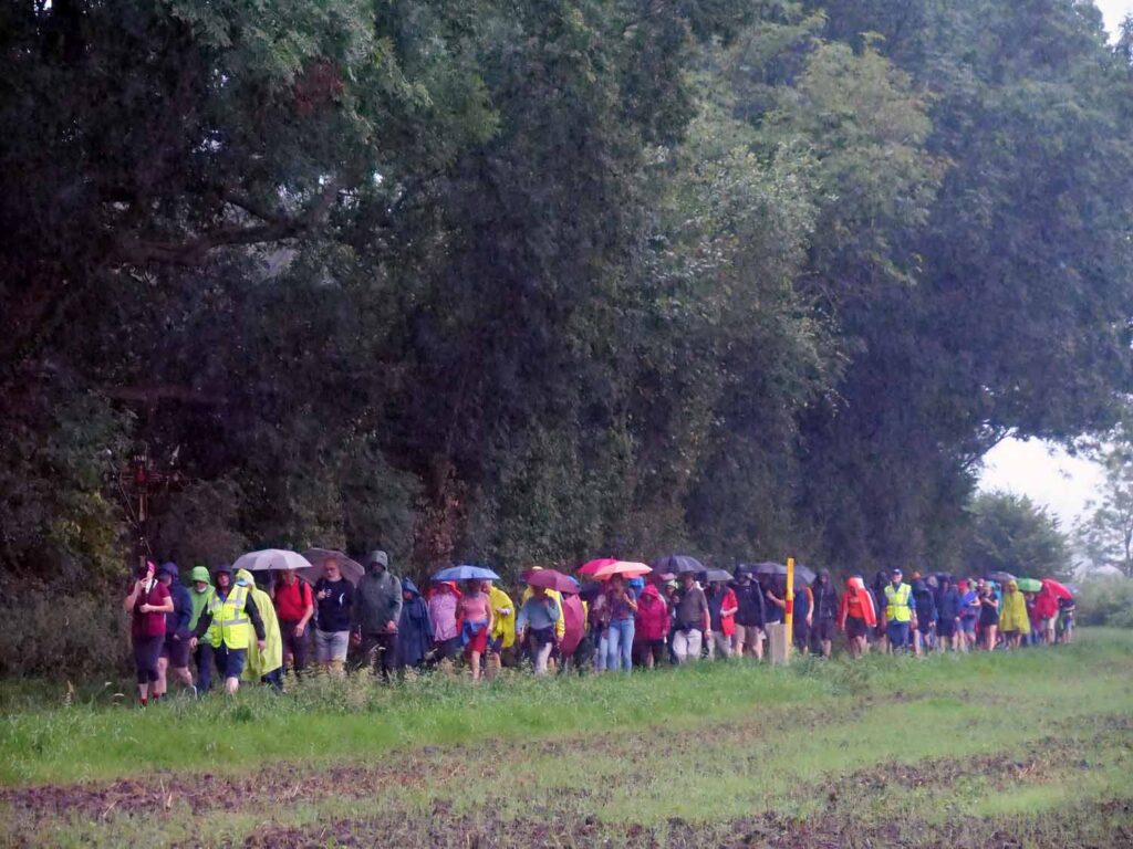 Dem grauen Wetter trotzten die Wallfahrer mit bunter Regenkleidung und Gesang. – Foto: Schwarze